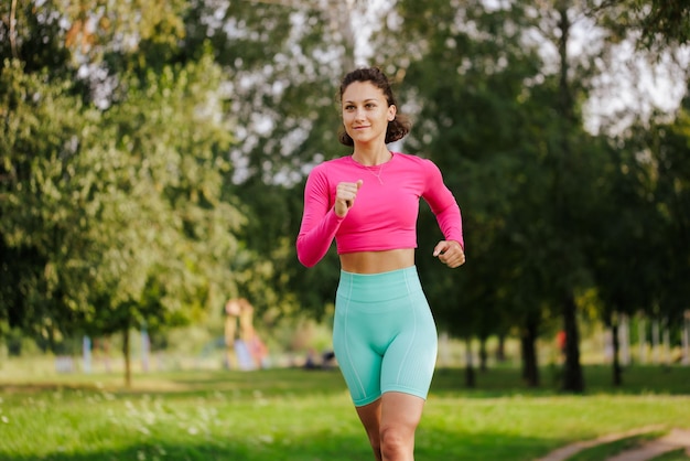 Una joven con ropa brillante practica deportes en un parque en la naturaleza