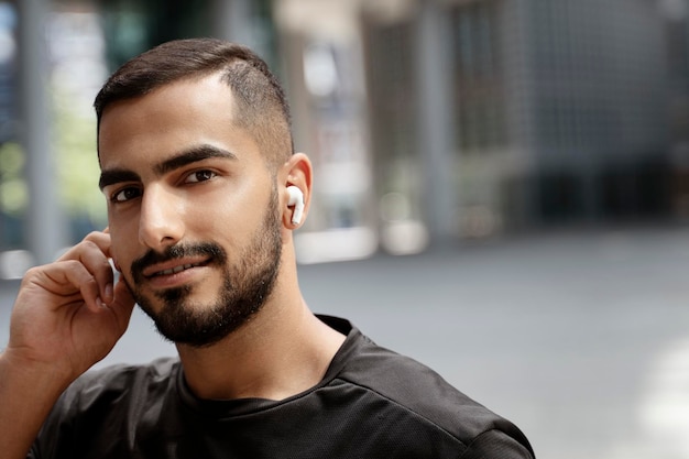 Joven en ropa casual escuchando música en auriculares y mirando a la cámara