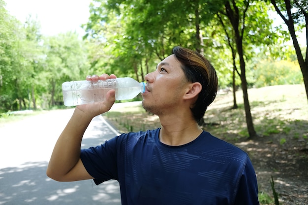 Joven en ropa deportiva bebiendo agua de una botella después del ejercicio