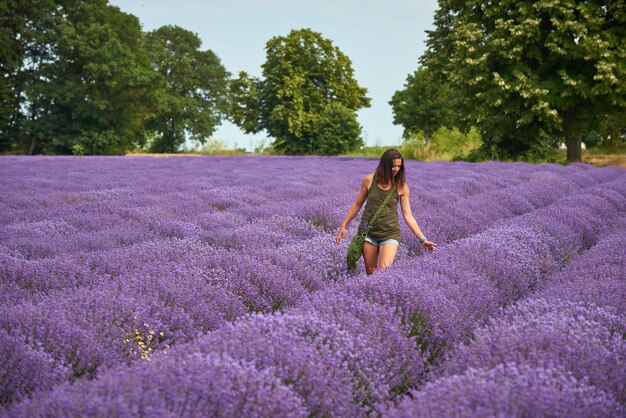 Una joven con ropa informal camina por un floreciente campo de lavanda