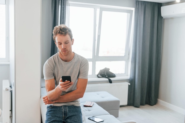 Un joven con ropa informal está adentro controlando la tecnología del hogar inteligente