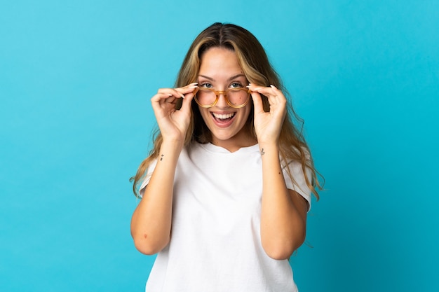 Joven rubia aislada con gafas y sorprendida