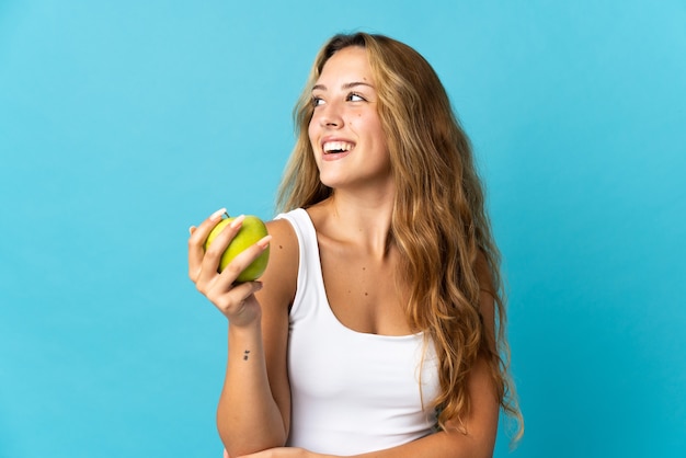 Joven rubia aislada con una manzana y feliz