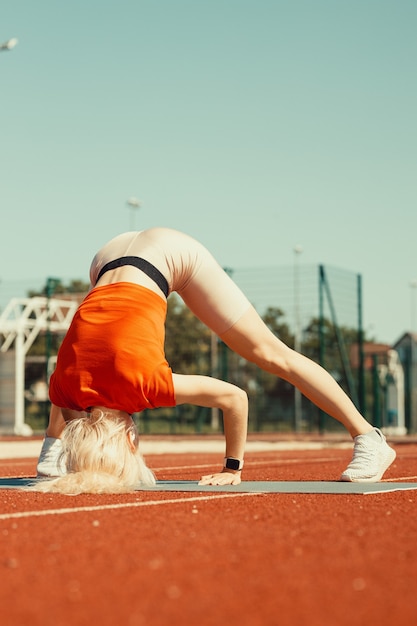 Joven rubia aprende a mantener el equilibrio en el pino y la cabeza