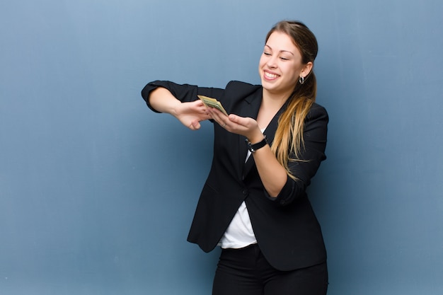 Joven rubia con billetes de dólar contra la pared del grunge