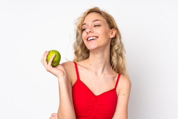 Joven rubia en blanco con una manzana y feliz