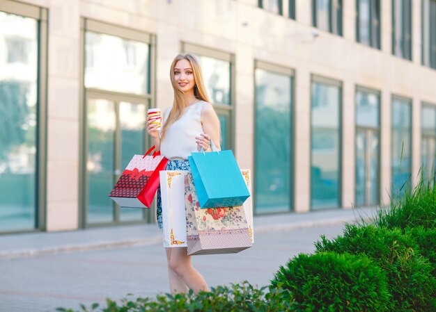 joven rubia, con bolsas de compras saliendo de la tienda.