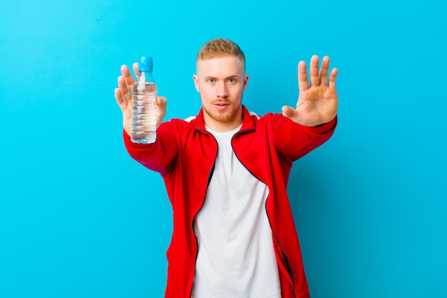 Joven rubia con una botella de agua con ropa deportiva