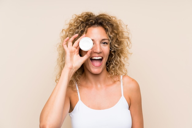 Joven rubia con cabello rizado con crema hidratante