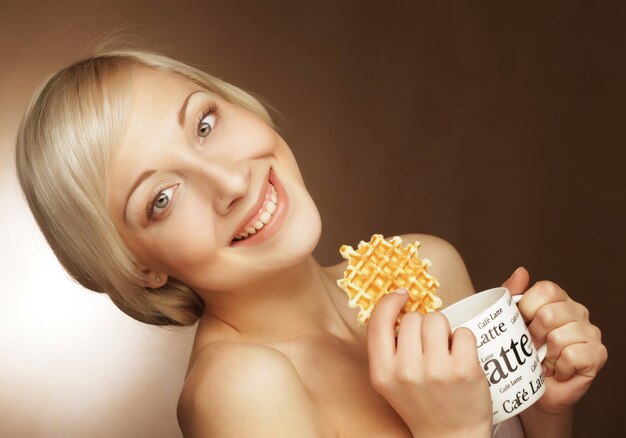 Joven rubia con café y galletas