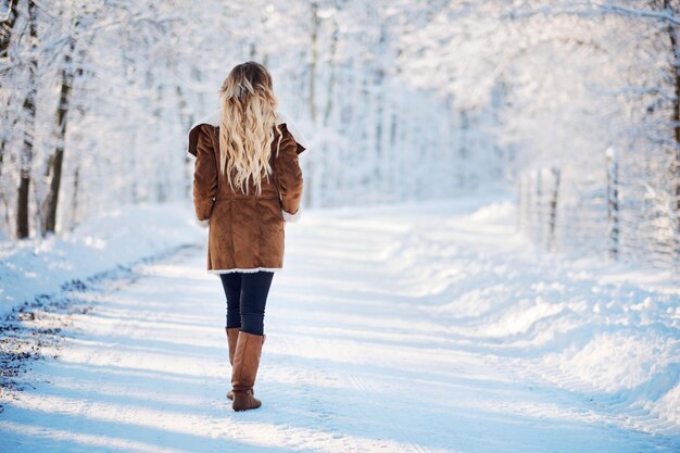 Una joven rubia caminando por el parque de invierno.