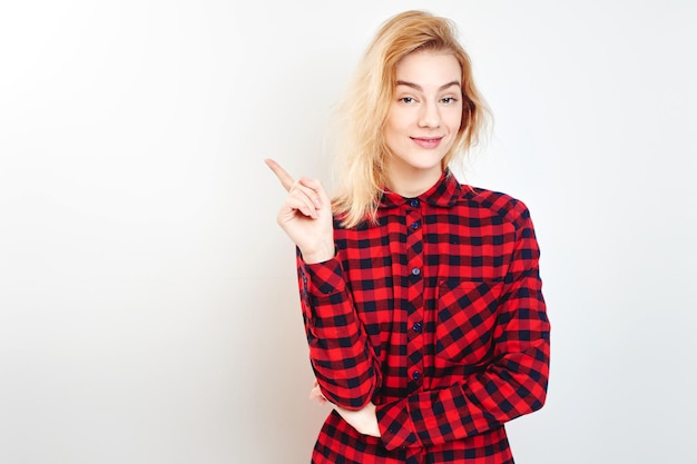 Una joven rubia con camisa roja apuntando con su dedo en el fondo