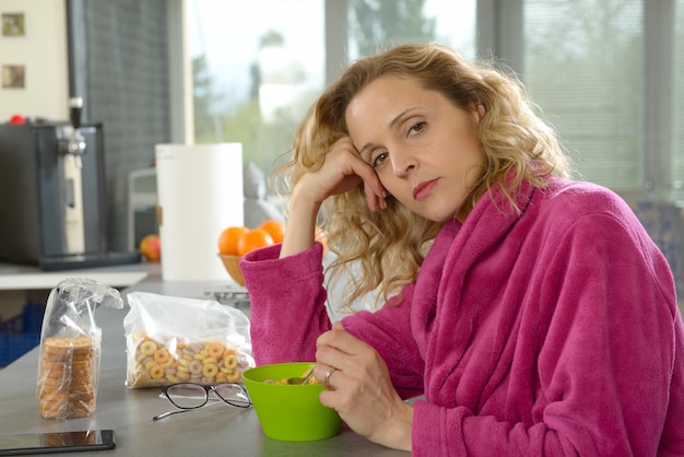 Joven rubia comiendo cereales en la mañana