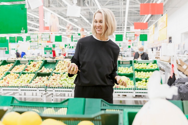 Joven rubia compra fruta en el supermercado.