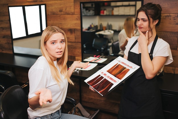 Joven rubia confundida no puede elegir el color de cabello de la paleta