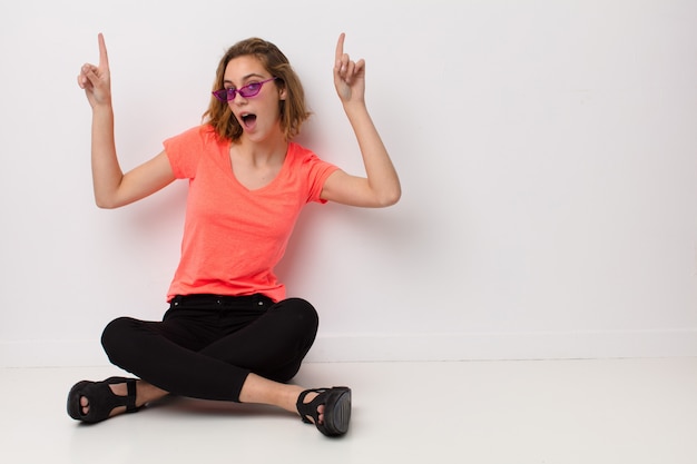 Joven rubia contra la pared de color plano