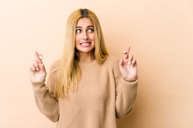 Joven rubia cruzando los dedos para tener suerte