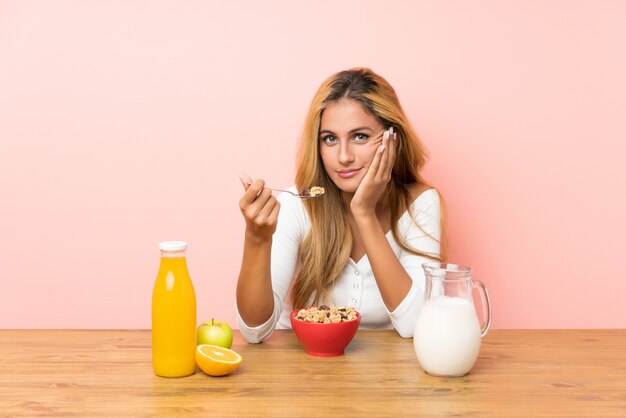 Joven rubia desayunando leche