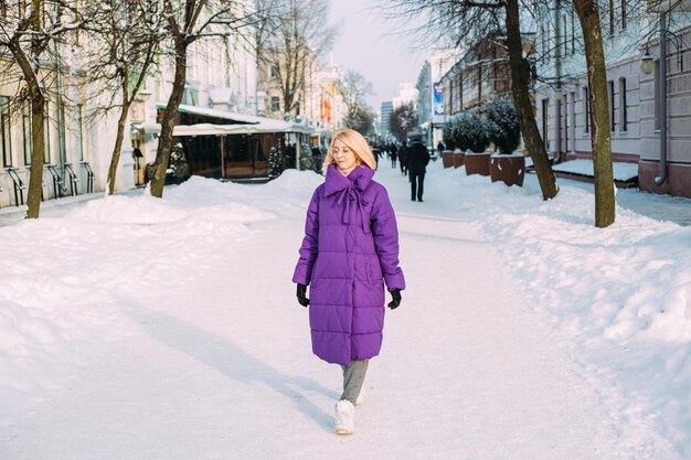 Joven rubia elegante con gafas en la calle en la nieve.