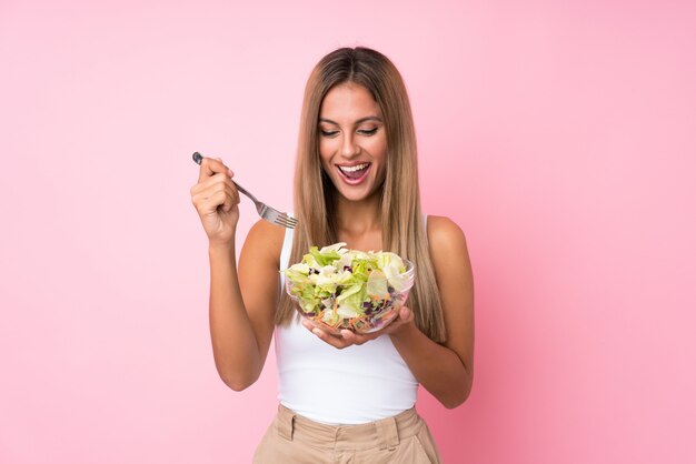 Foto joven rubia con ensalada sobre fondo aislado