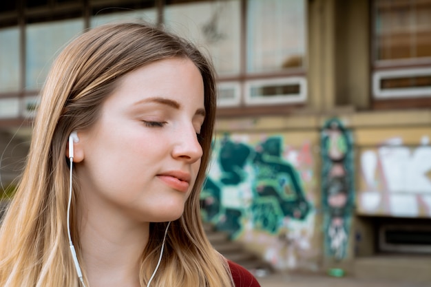 Joven rubia escuchando música con auriculares