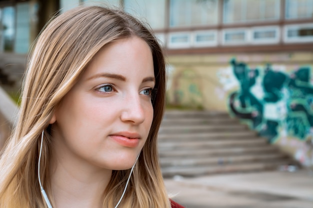 Joven rubia escuchando música con auriculares