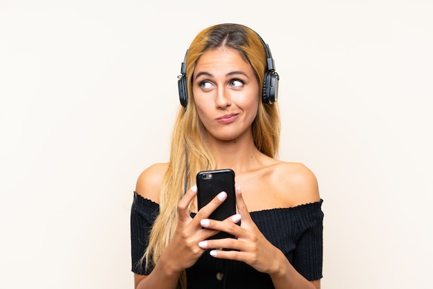 Joven rubia escuchando música con un móvil y pensando