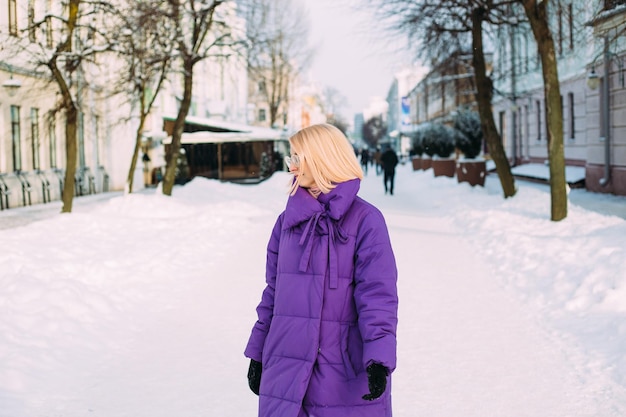 Joven rubia con estilo con gafas en la calle en la nieve.