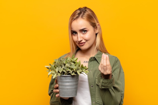 joven rubia haciendo capice o gesto de dinero, diciéndole que pague sus deudas!