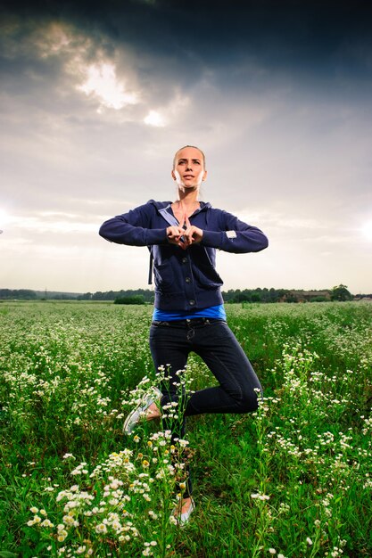 Joven rubia haciendo yoga en un prado