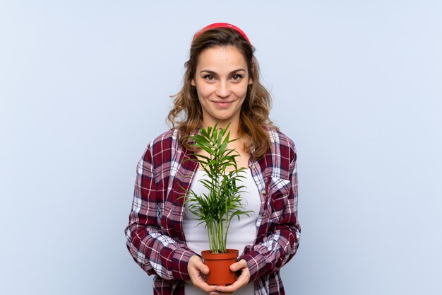 Joven rubia jardinero chica sosteniendo una planta