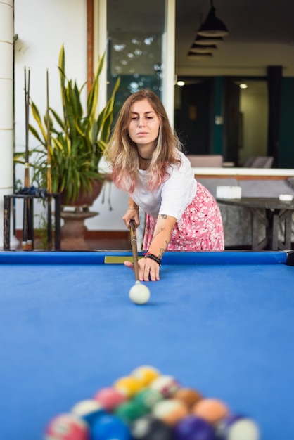 Una joven rubia jugando al billar en el patio trasero.