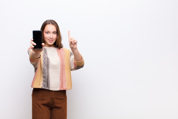 Joven rubia linda chica sosteniendo un teléfono inteligente