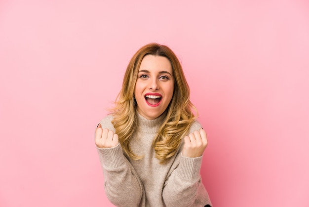 Joven rubia linda mujer vistiendo un suéter animando despreocupado y emocionado