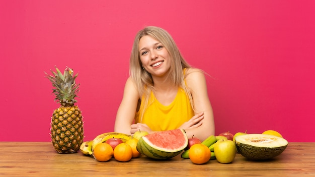 Joven rubia con muchas frutas riendo