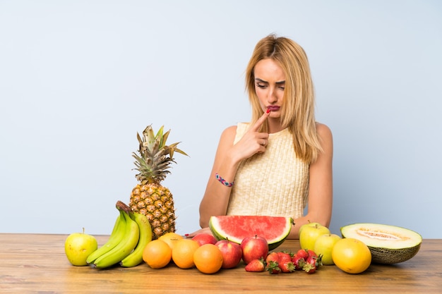 Joven rubia con muchas frutas