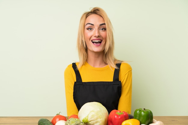 Joven rubia con muchas verduras con expresión facial sorpresa