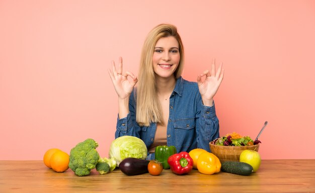 Joven rubia con muchas verduras en pose zen