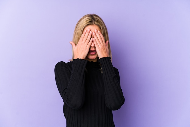 Joven rubia mujer caucásica miedo cubriendo los ojos con las manos.