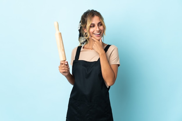 Joven rubia mujer cocina uruguaya aislada mirando hacia el lado y sonriendo