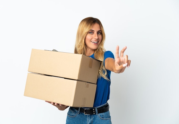 Joven rubia mujer de entrega uruguaya en blanco sonriendo y mostrando el signo de la victoria