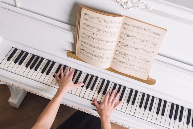 Una joven rubia no toca el piano blanco.