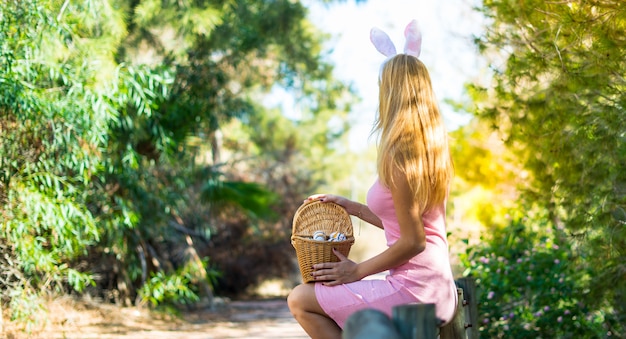 Joven rubia con orejas de conejo y coloridos huevos de Pascua