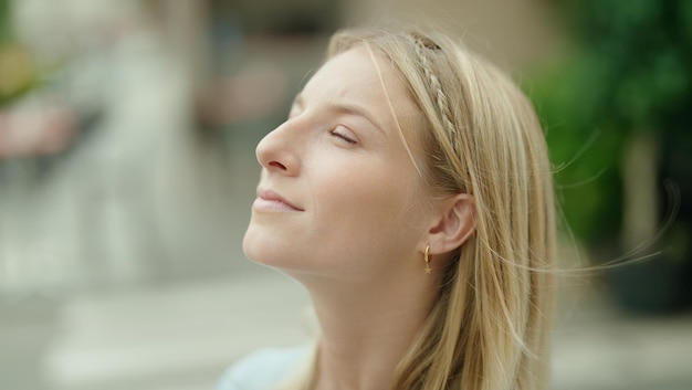 Joven rubia respirando con los ojos cerrados en la calle