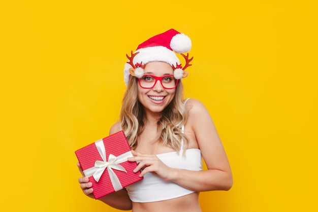 Una joven rubia sexy un sombrero rojo de Santa Claus de Navidad con gafas divertidas tiene una caja de regalo