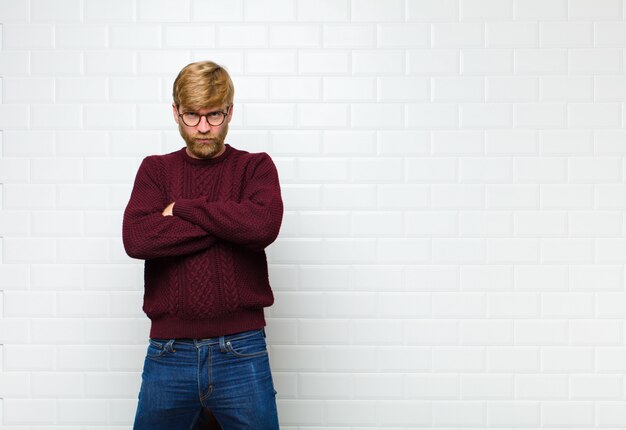 Joven rubia se siente disgustado y decepcionado, se ve serio, molesto y enojado con los brazos cruzados contra la pared de azulejos vintage