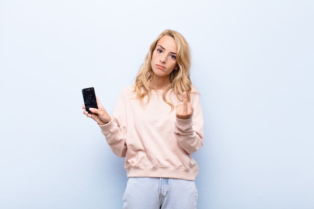 joven rubia con smartphone volteando el dedo medio