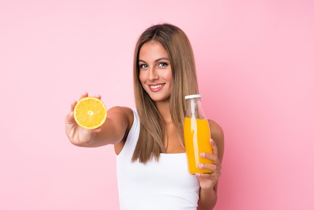 Joven rubia sobre aislado sosteniendo una naranja