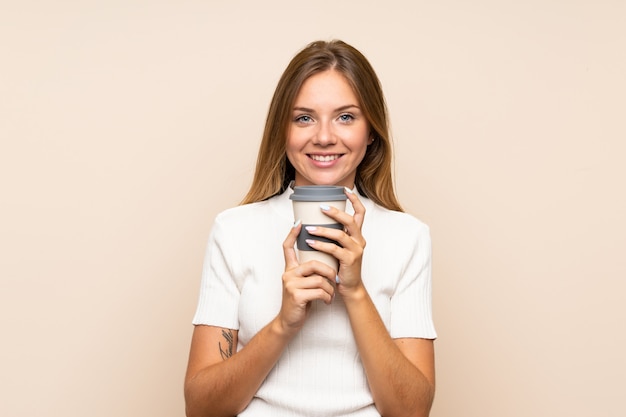 Joven rubia sobre pared aislada con café para llevar