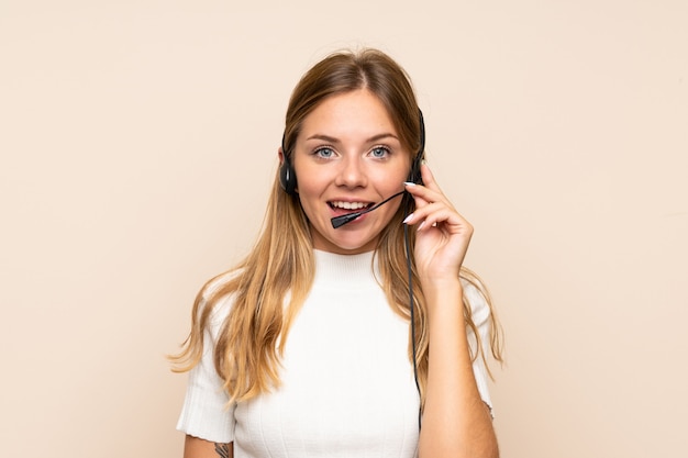 Joven rubia sobre pared aislada trabajando con auriculares